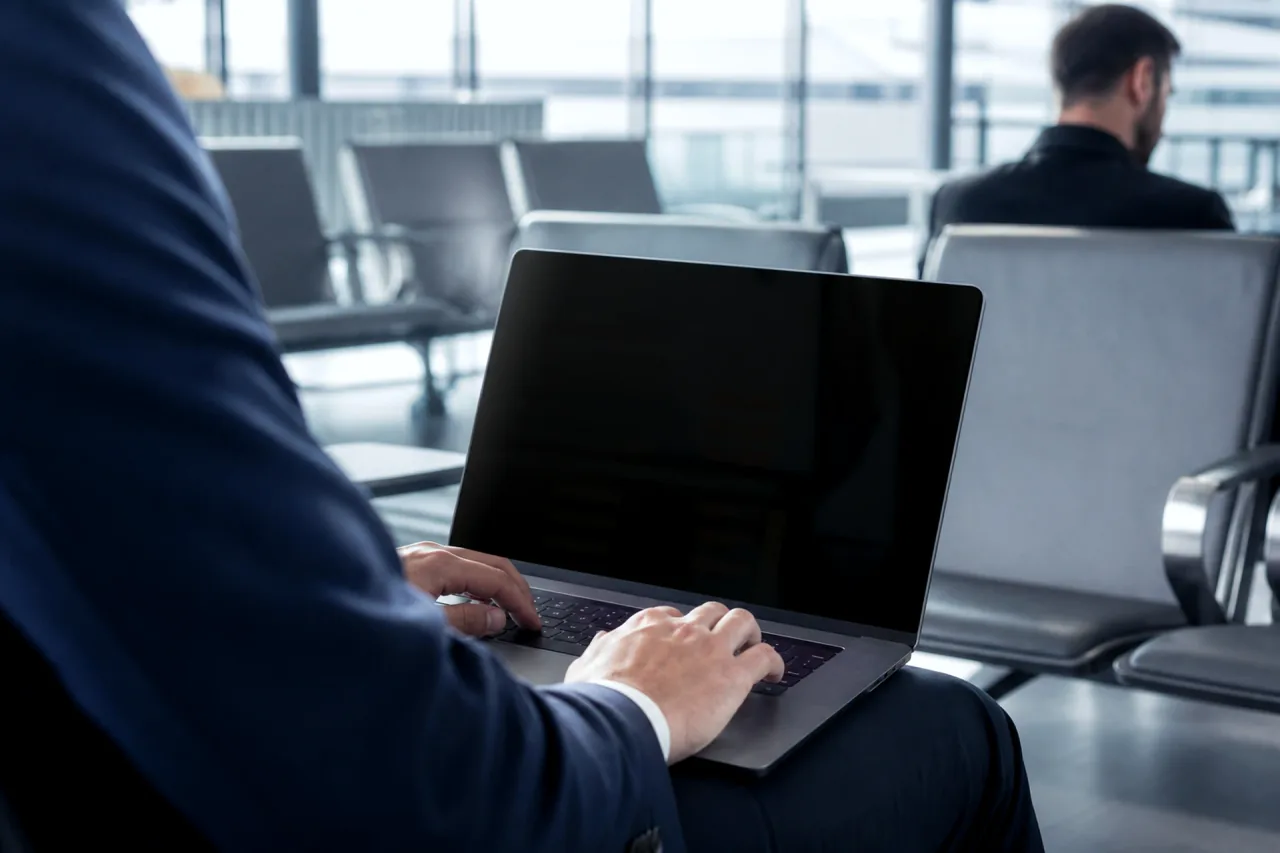 Traveler using a laptop with a uniformly dark privacy-protected screen