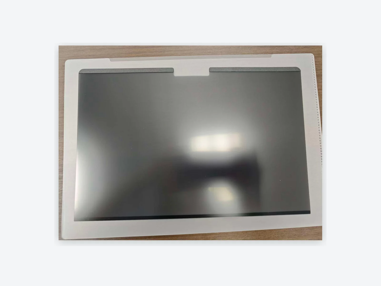 Magnetic privacy filter laid flat with a top strip and camera notch