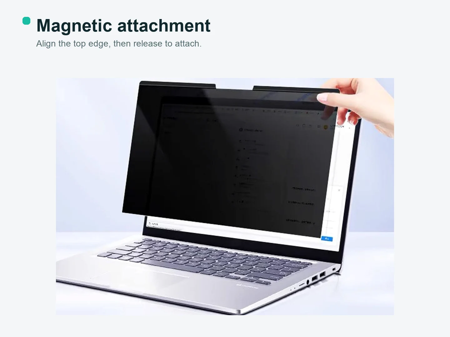 Hand lifting a magnetic privacy filter from the top edge of an unbranded laptop display.
