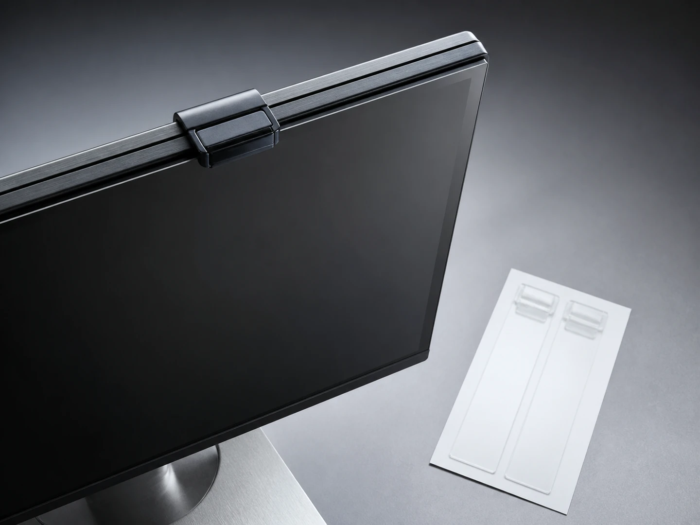 Monitor privacy filter secured by a top clip with separate clear adhesive mounting strips nearby