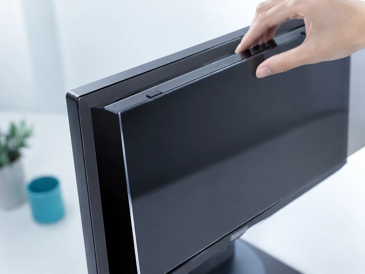 Rigid acrylic privacy panel supported over the top edge of a desktop monitor
