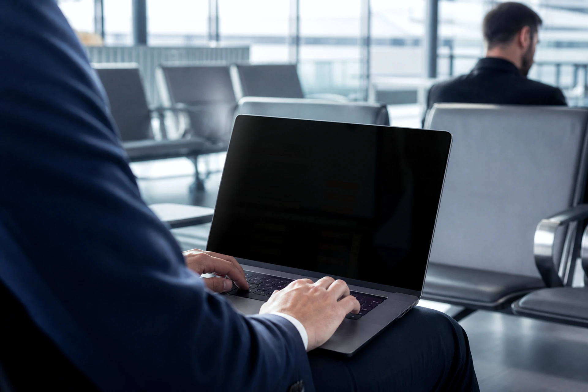 Traveler using a laptop with a uniformly dark privacy-protected screen