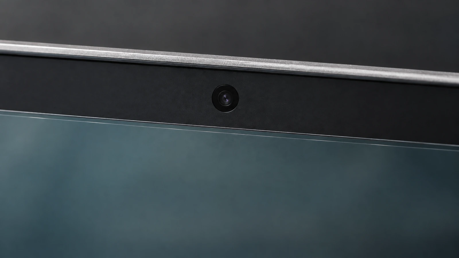 Close-up of a laptop camera above the straight upper edge of a thin screen filter.